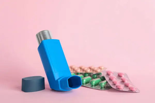 stock image Inhaler and pills on pink background, closeup with space for text. Asthma treatment