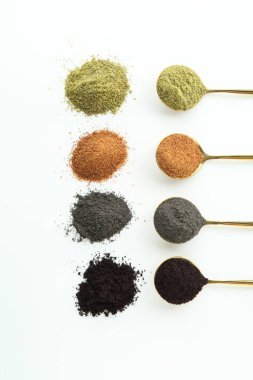 Beyaz arka planda farklı süper yiyecek tozları olan kaşıklar, düz konum