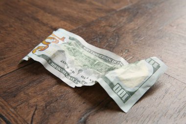 Tahta masanın üzerine buruşmuş bir dolar banknot, yakın plan.