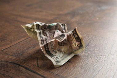 Tahta masanın üzerine buruşmuş bir dolar banknot, yakın plan.
