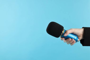 Açık mavi arka planda mikrofonu olan kadın, yakın plan. Metin için boşluk