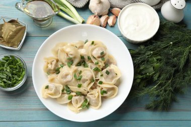 Mavi ahşap masada servis edilen yeşil soğanlı leziz pelmeni.