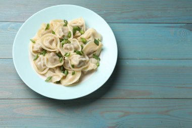 Yeşil soğanlı leziz pelmeni mavi ahşap masa, üst manzara. Metin için boşluk
