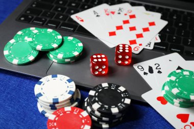 Poker fişleri, dizüstü bilgisayar, mavi masada kağıt ve zarlar. Çevrimiçi oyun