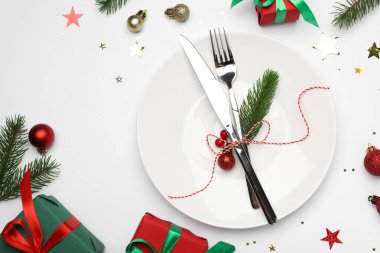 Tabak, çatal bıçak takımı ve beyaz arka planda şenlikli Noel sofrası, düz yatış