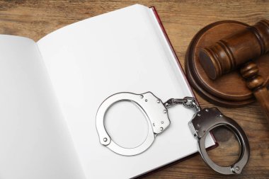 Kitap, yargıç tokmağı ve kelepçeler ahşap masada, düz yatar