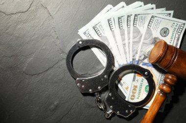 Dolar banknotlu kelepçeler ve gri desenli masa üzerinde tahta tokmak, düz yatış. Metin için boşluk