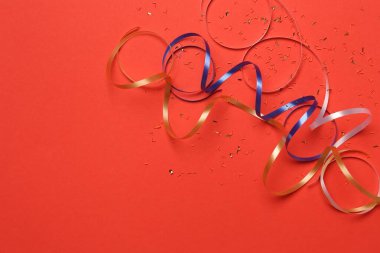 Kırmızı arka planda parlak konfeti ve parti flamaları var. Metin için boşluk