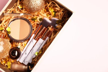 Makyaj fırçaları, dekoratif kozmetik, parfüm ve pembe arka planda Noel dekorasyonu. Metin için boşluk