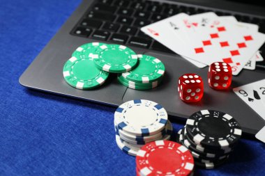 Poker fişleri, dizüstü bilgisayar, mavi masada kağıt ve zarlar. Çevrimiçi oyun