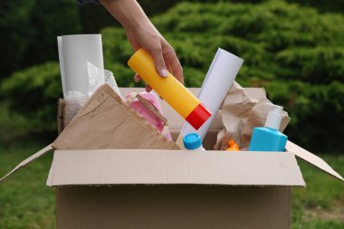 Geri dönüşüm konsepti. Dışarıdaki karton kutuya plastik şişe koyan kadın, yakın plan.