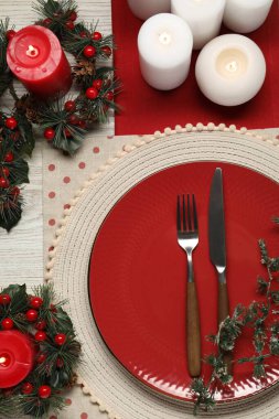 Tabak, çatal bıçak takımı ve ahşap masa üzerindeki şenlikli Noel sofrası.