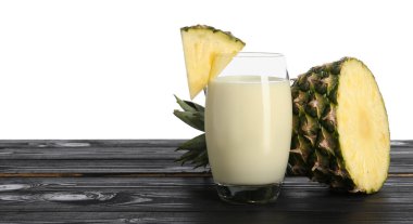 Bardakta lezzetli ananas püresi ve beyaz arka planda tahta masada meyve dilimleri. Metin için boşluk