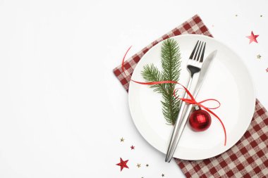 Beyaz arka planda tabak, çatal bıçak, peçete ve şenlik dekoruyla Noel sofrası. Metin için boşluk