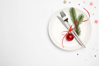 Beyaz arka planda tabak, çatal bıçak takımı ve şenlik dekoruyla Noel sofrası, üst manzara. Metin için boşluk