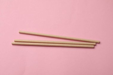 Pembe arka planda bambu pipetleri, üst görünüm