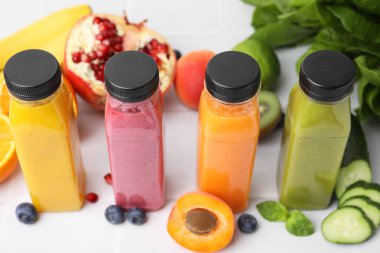 Cam şişeler dolusu lezzetli meyve püresi ve beyaz fayanslı masada farklı ürünler.