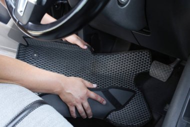 Gri lastik araba paspasını otomatikten alan adam, yakın plan.