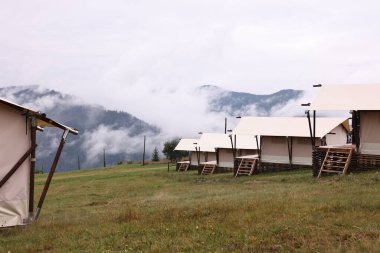 Dağlarda sisle kaplı bir sürü çadır ve orman var. Glamping alanı