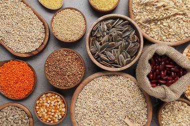 Gri masa üzerinde farklı tipte tahıl, tohum ve baklagiller, düz yatak