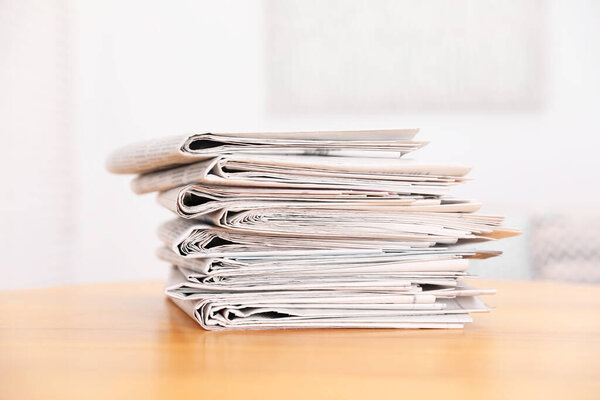 Stack of many newspapers on wooden table
