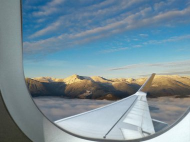 Airplane flying over mountains, beautiful view from window clipart