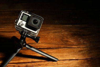 Ahşap yüzeyde modern aksiyon kamerası ve tripod. Metin için boşluk
