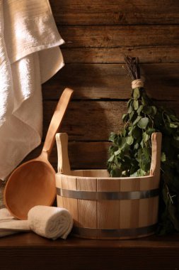 Sauna ekipmanları. Kova, kepçe, huş ağacı çırpı ve havlular kapalı masa üzerinde.