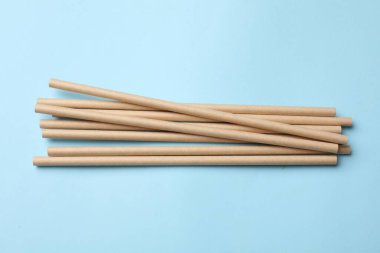 Açık mavi arka planda bambu içme pipetleri, üst görünüm