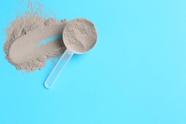 Protein tozu ve açık mavi arka planda kepçe, üst manzara. Metin için boşluk
