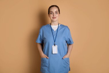 Koyu bej arka planda rozeti olan profesyonel hemşire.