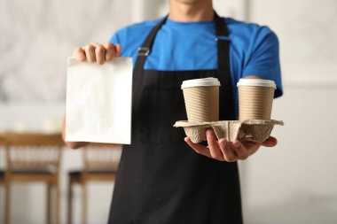 Kese kağıdı ve bardaklı fast-food işçisi, yakın plan.