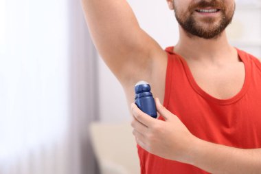 Gülümseyen adam evde deodorant sürüyor, yakın plan. Metin için boşluk