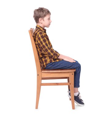 Beyaz arka planda sandalyeye oturan doğru duruşu olan çocuk