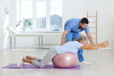 Rehabilitasyon merkezinde kıdemli bir hastayla çalışan fizyoterapist.