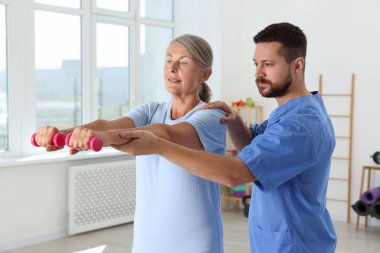 Rehabilitasyon merkezinde fizyoterapist gözetiminde egzersiz yapan kıdemli hasta.