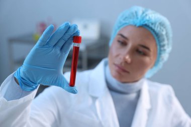 Laboratuvar testi. Kapalı alanda kan örneği olan test tüpü tutan doktor, seçici odaklanma