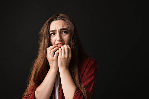 Portrait of scared woman on black background. Space for text