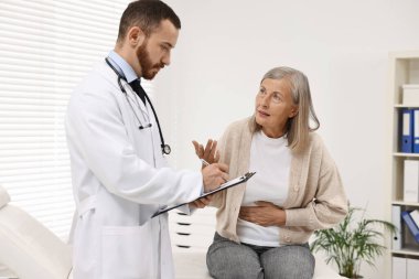 Klinikte mide ağrısı olan kıdemli bir hastaya danışmanlık yapıyor.