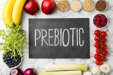 Tahtada Prebiyotik ve beyaz mermer masa üzerinde farklı ürünler var.