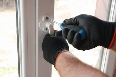 Tamirci içeride tornavidayla yeni pencere kuruyor.