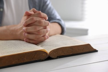 İncilli adam beyaz tahta masada dua ediyor, yakın plan.