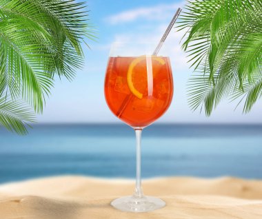 Lezzetli Aperol Spritz kokteyli, palmiye yaprakları ve altın kumu olan yaz plajı.