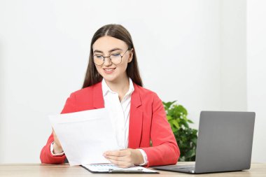 Bütçe planlaması. Ofisteki ahşap masada evrakları ve bilgisayarı olan genç bir kadın.