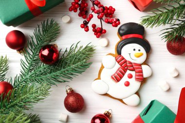 Kardan adam şeklinde lezzetli kurabiyeler, marşmelovlar ve beyaz ahşap masa üzerinde Noel süsü.