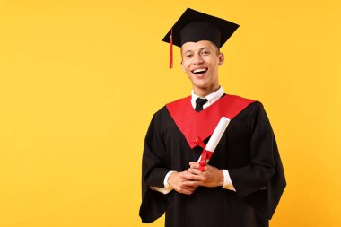 Mezun olduktan sonra turuncu arka planda diploması olan mutlu bir öğrenci. Metin için boşluk