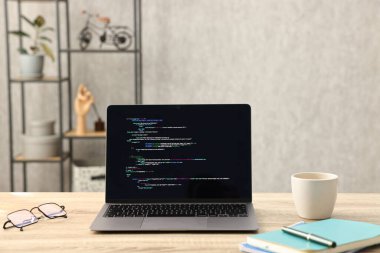 Programcının işyeri. Tamamlanmamış kodu olan modern bir bilgisayar, gözlüklü bardak ve kırtasiye malzemesi.