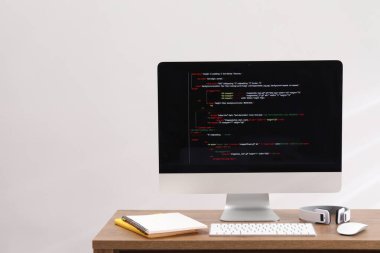 Programcının işyeri. Tamamlanmamış kod, kulaklık ve kırtasiye malzemesi olan modern bir bilgisayar.