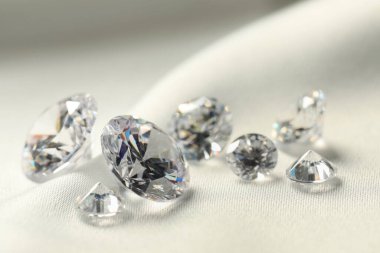 Many beautiful shiny diamonds on white fabric, closeup clipart