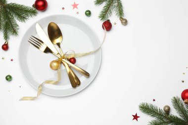 Beyaz arka planda tabak, çatal bıçak takımı ve şenlik dekoruyla Noel sofrası. Metin için boşluk